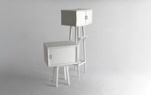 Two white wooden nightstands in their closed configuration, hosting small life scenes inside and outside, interpreted by miniature 1:87 scale figures