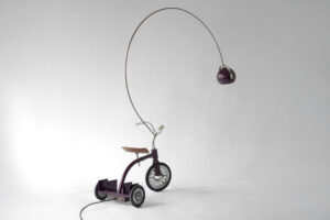 Rear three-quarter view of the 1960s tricycle showing metal bookrack, curved arc lamp and restored frame