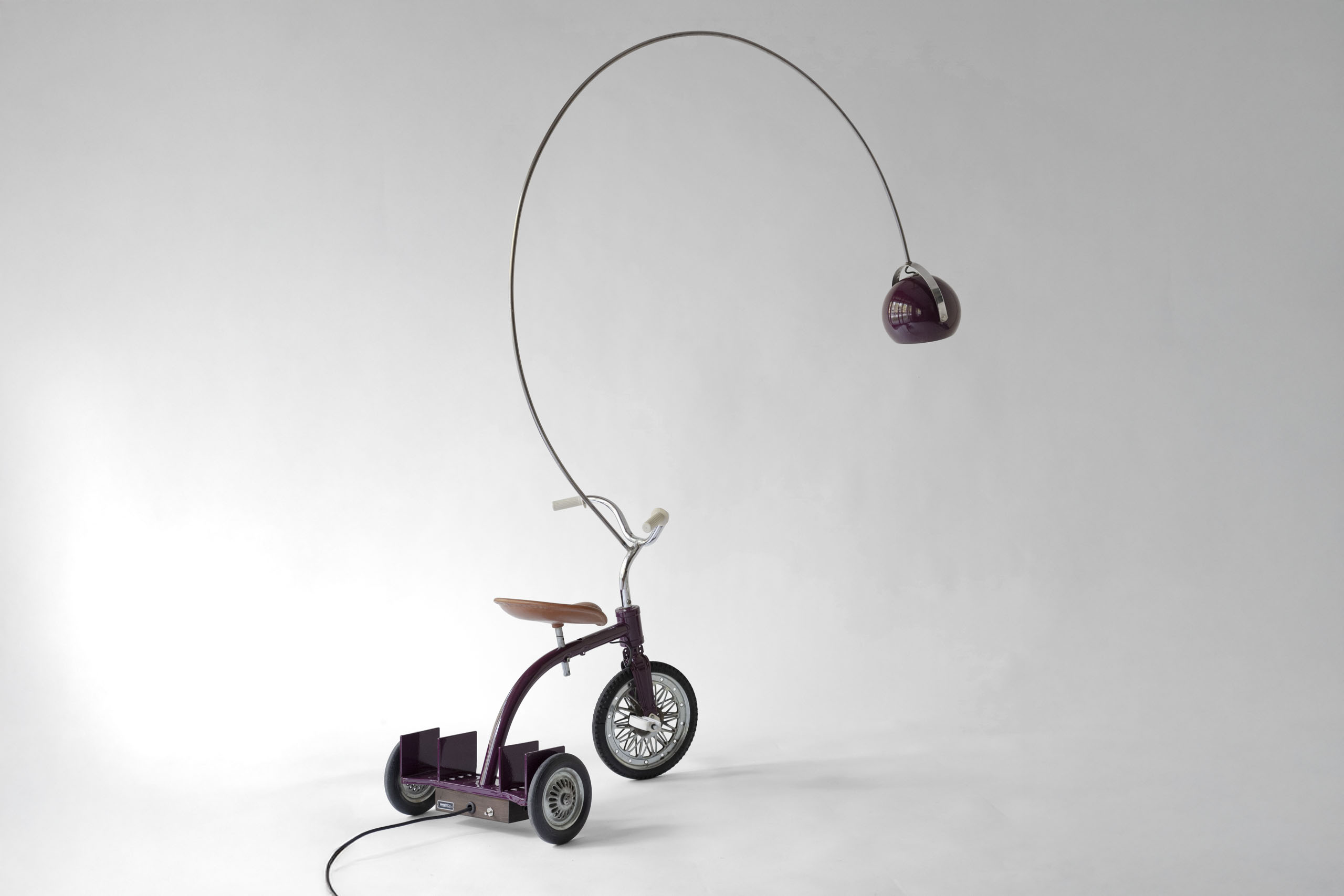Rear three-quarter view of the 1960s tricycle showing metal bookrack, curved arc lamp and restored frame