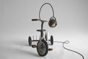 Front view of Fausto, a 1960s tricycle transformed into a traveling lamp and bookshelf, shown from the front