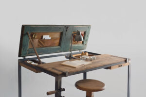 Open Indoor K table used as a desk, with restored wooden doors, leather pockets and a few objects on the surface