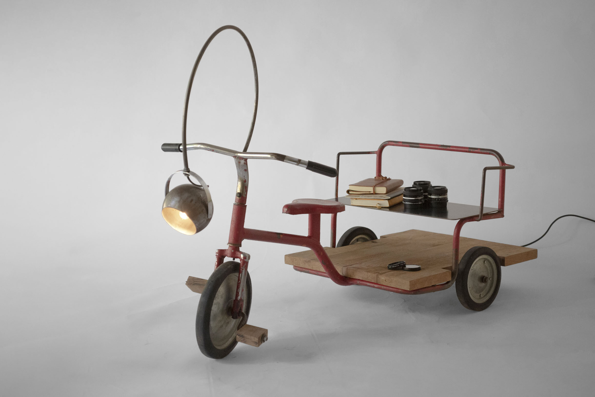 Authentic 1960s red Carrito tricycle transformed into a traveling library, shown with its light on and various objects displayed