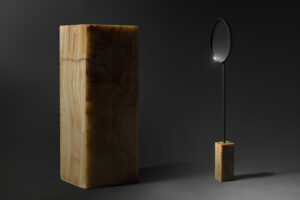 floor standing mirror with orange onyx base in dark studio view