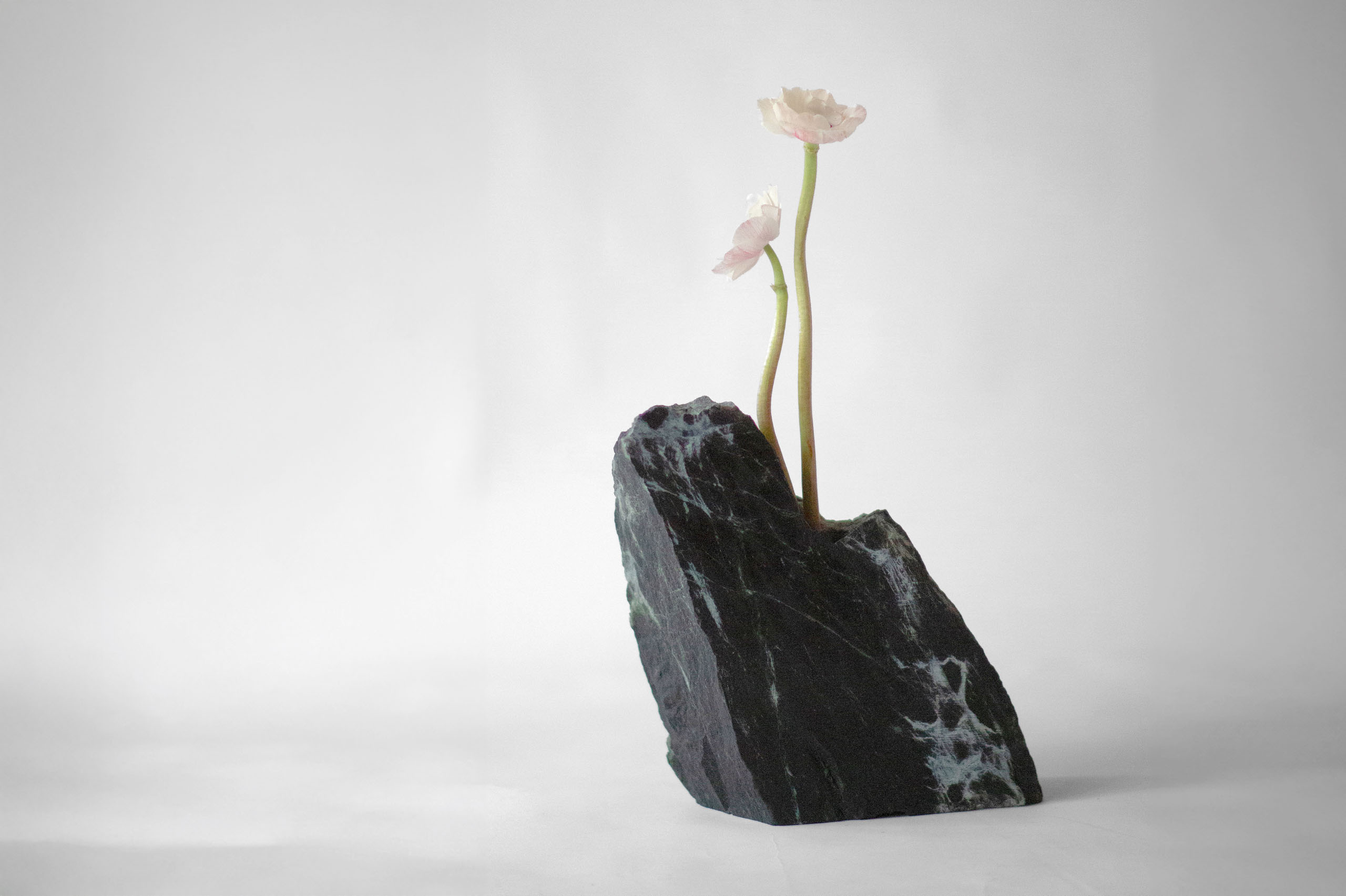Riquiqui Montaigne #1 sculptural vase in Verde Alpi marble with two pale flowers