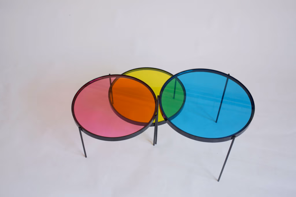CMYK coffee table by Manoteca, rotation sequence, frame 02: cyan disc rotating left, increasing overlap with the yellow disc, green intersection area expanding, magenta and yellow discs stationary.