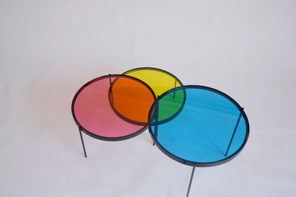 CMYK coffee table by Manoteca, rotation sequence 04: cyan disc continuing left, green intersection between cyan and yellow more pronounced, three-disc overlap beginning to form at centre, magenta and yellow discs stationary.