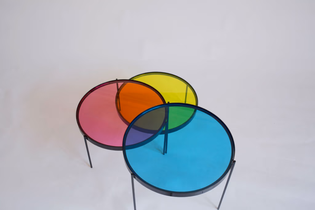 CMYK coffee table by Manoteca, rotation sequence 06: cyan disc at near-maximum overlap, triple intersection at centre fully formed, cyan-yellow and cyan-magenta secondary colours clearly visible, magenta and yellow discs stationary.