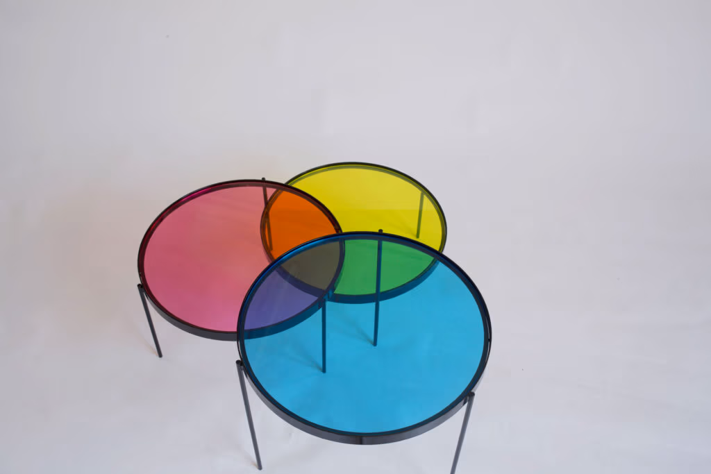 CMYK coffee table by Manoteca, rotation sequence 07: magenta disc beginning to rotate downward, cyan and yellow discs stationary, triple overlap at centre shifting, orange intersection between magenta and yellow reducing.