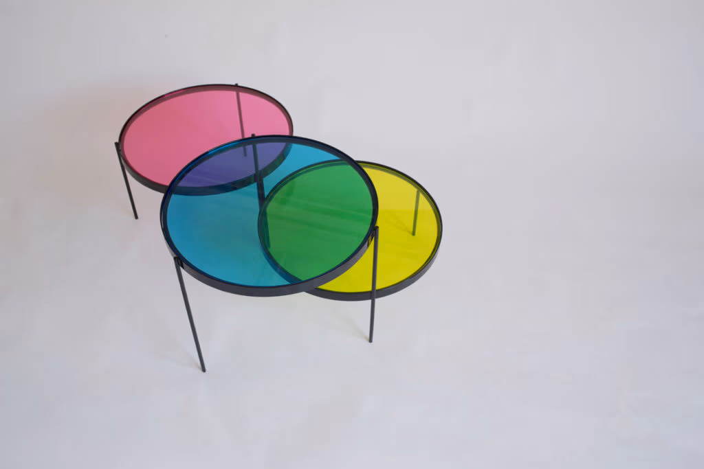 CMYK coffee table by Manoteca, rotation sequence 13: magenta disc at far right position, cyan and yellow discs stationary, green cyan-yellow overlap dominant, magenta and cyan overlaps minimal, three discs approaching open configuration.