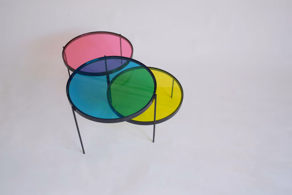 CMYK coffee table by Manoteca, rotation sequence 14: magenta disc rising upward, cyan and yellow discs stationary, green cyan-yellow overlap dominant, magenta progressively disengaging from central overlap area.