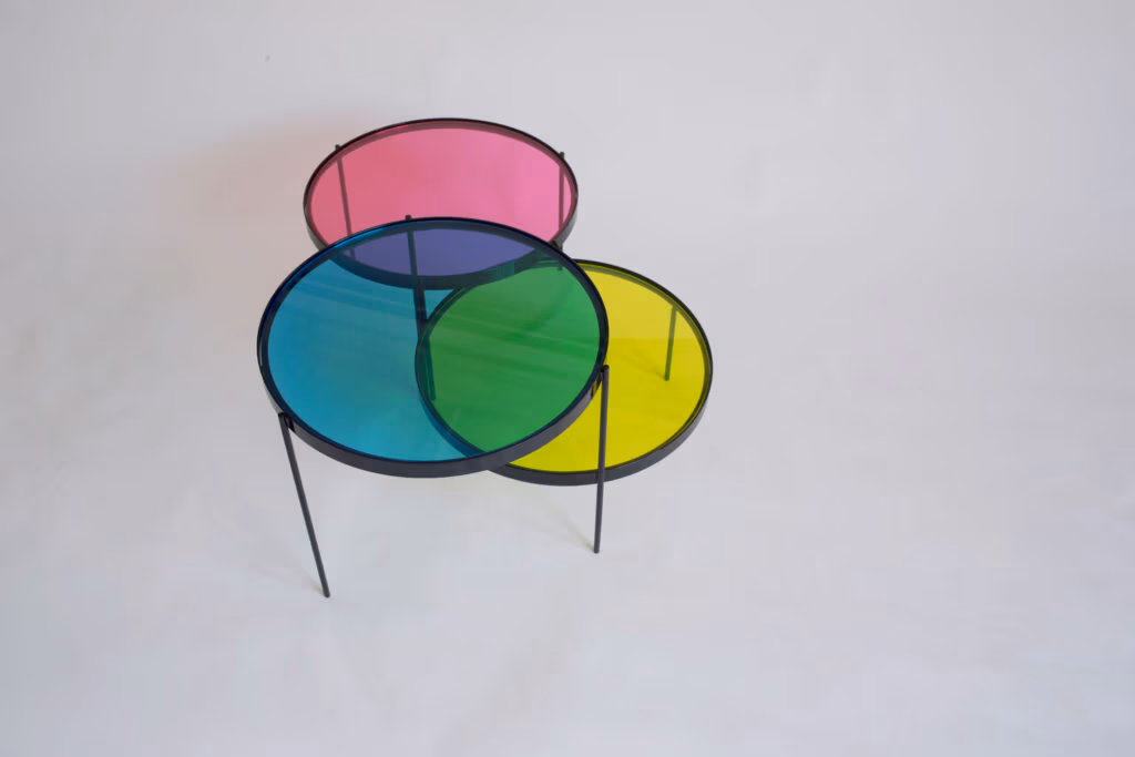 CMYK coffee table by Manoteca, rotation sequence 15: magenta disc continuing upward, cyan and yellow discs stationary, three discs approaching fully open position, overlaps reduced to minimal intersections.