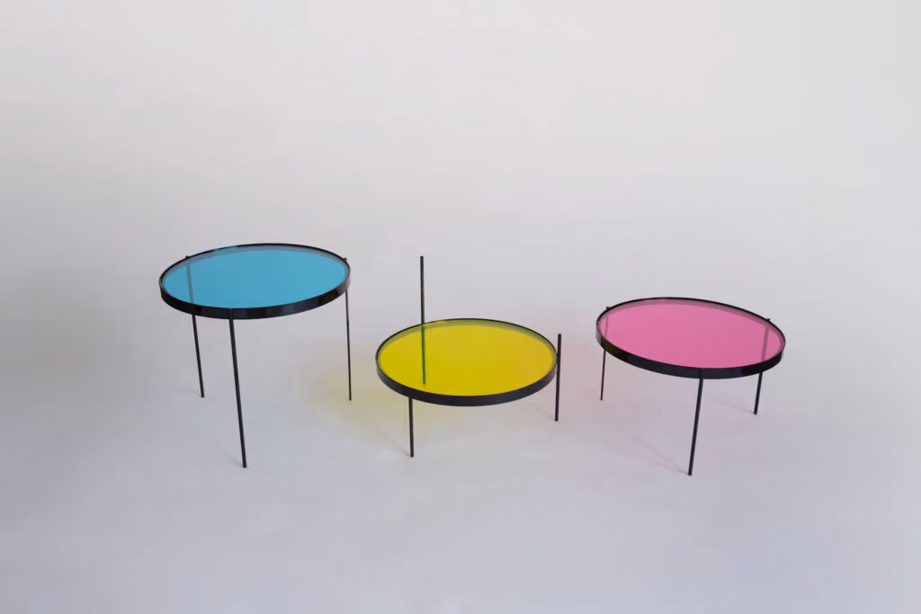 CMYK coffee table by Manoteca, assembly sequence 01: three glass discs on black metal legs in fully open position, cyan, yellow and magenta discs at maximum distance.