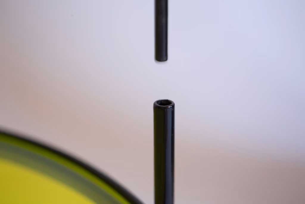 CMYK coffee table by Manoteca, assembly sequence 02: close-up of black metal male leg inserting into the female leg socket, forming the rotating pin joint.