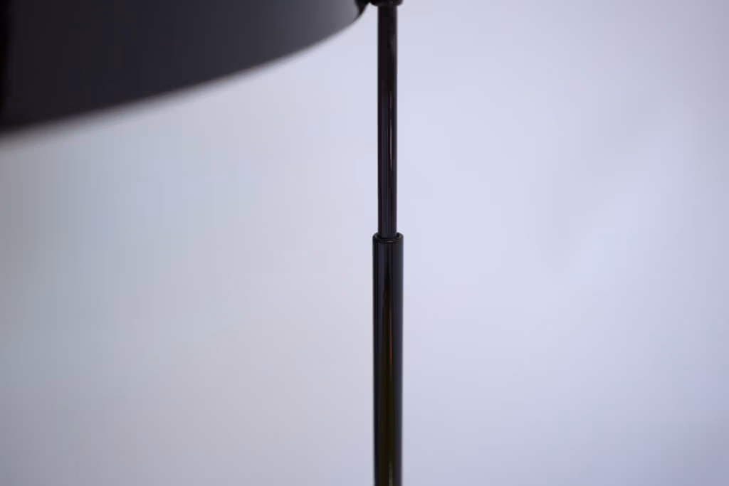 CMYK coffee table by Manoteca, assembly sequence 06: close-up of black metal male leg beginning to insert into female socket on the cyan glass disc, structural detail.