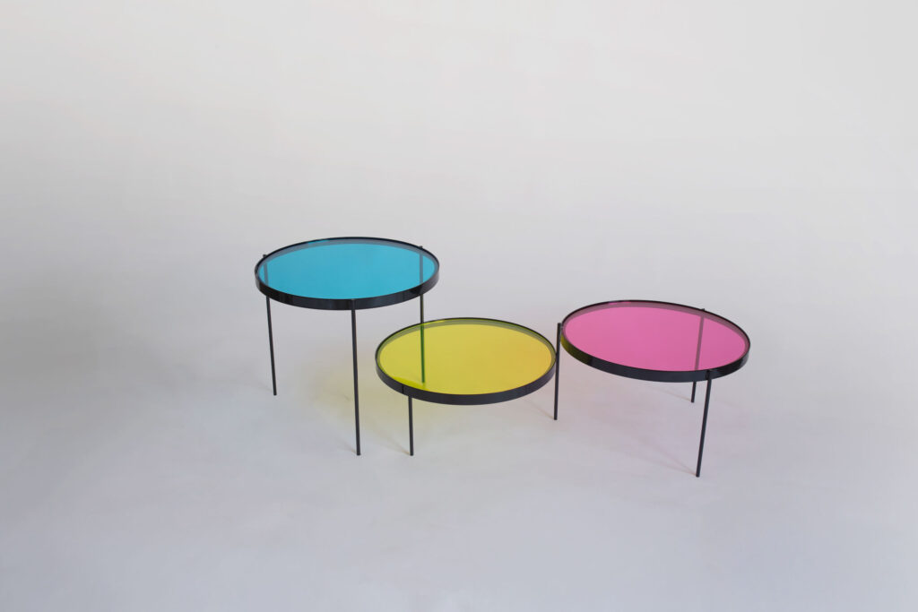 CMYK coffee table by Manoteca, assembly sequence 10: fully assembled table, three glass discs on black metal legs in open position, cyan, yellow and magenta at maximum distance.